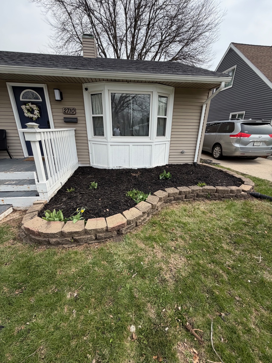 After: fresh black mulch in stone-walled bed